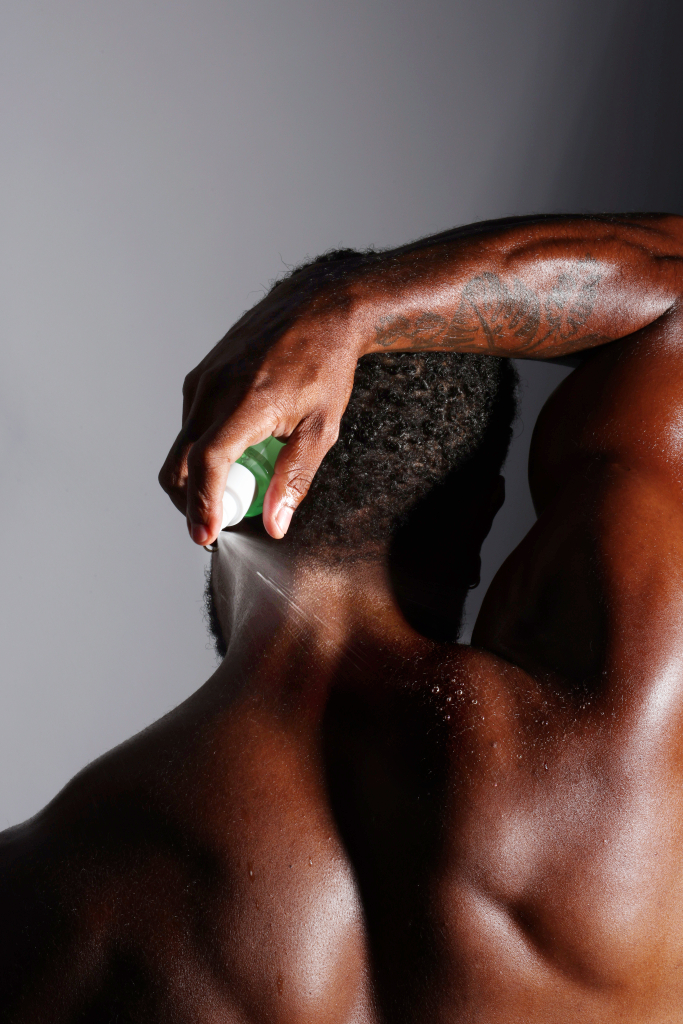 um homem usa o spray antiacne corporal nas costas